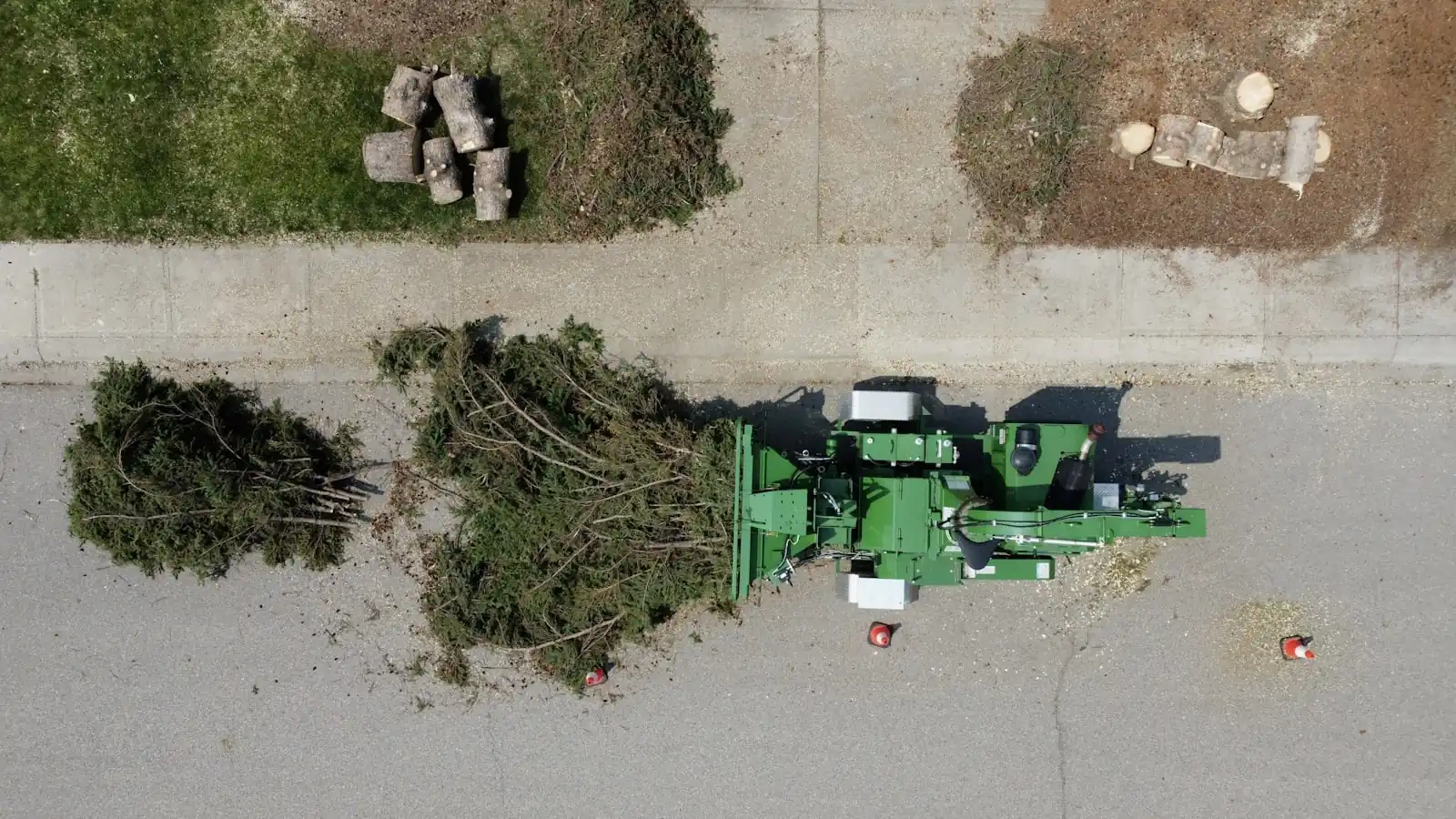 Tree care crew operating a wood chipper and machinery beside their service truck on a job site